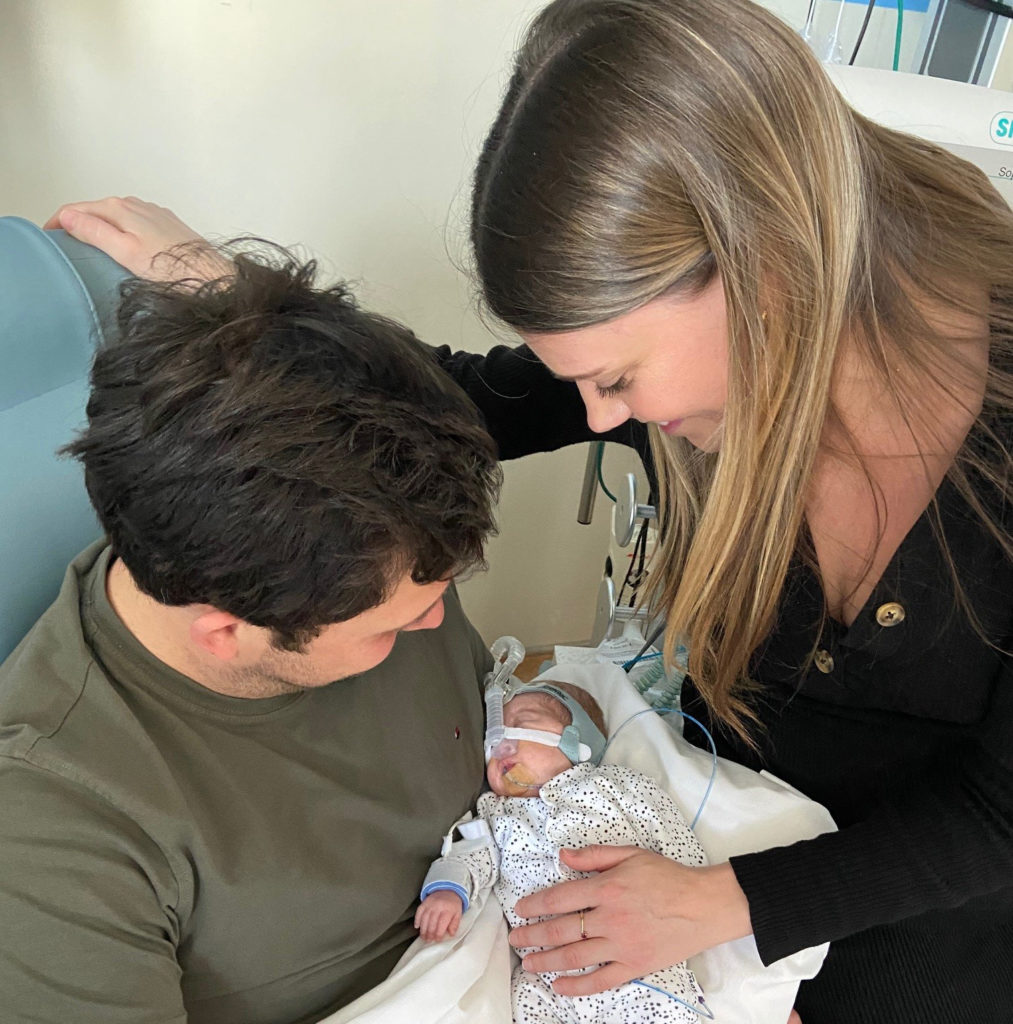 Two parents hold newborn baby
