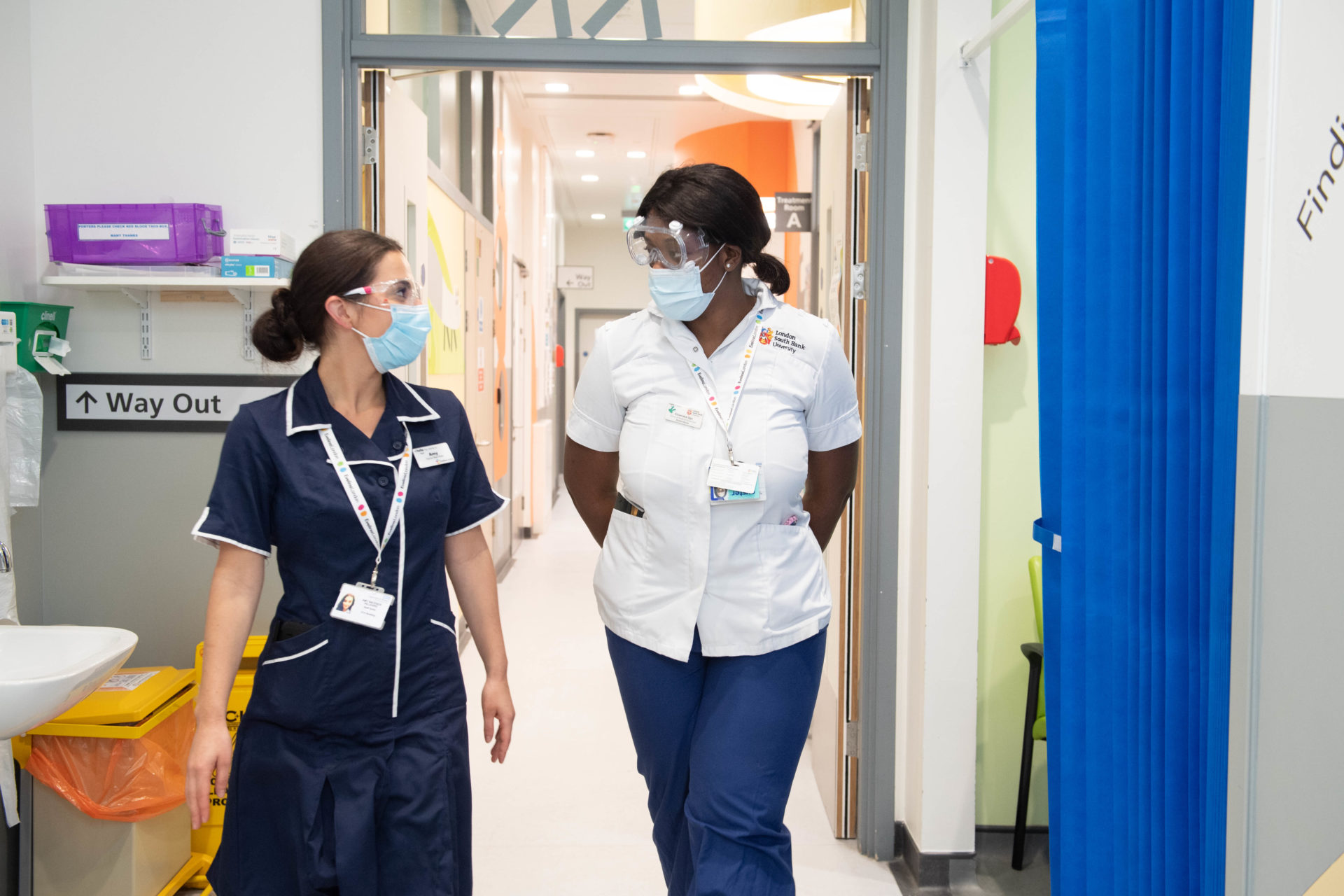 Two nurses walk and talk inside a hospital