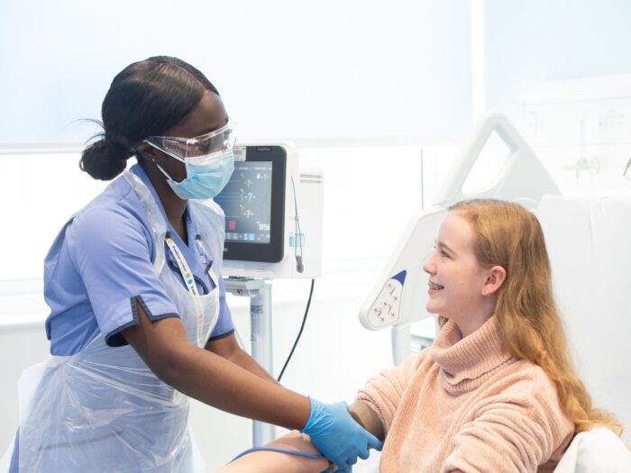 Hospital worker speaks to girl smiling in hospital bed