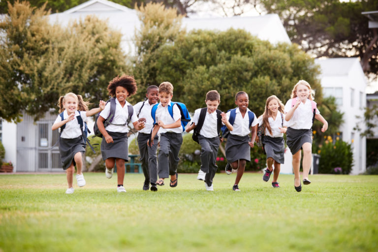 Excited school Pupils Wearing Uniform Running Across Field At Break Time