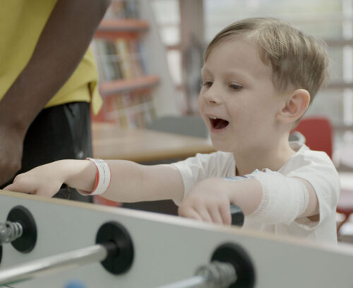 Image of a boy playing table football in the hospital