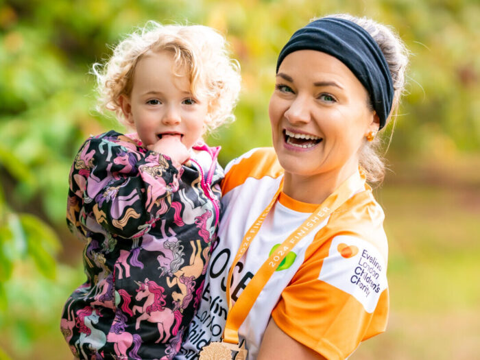 Rose smiling wearing a black headband and an orange Evelina London Children