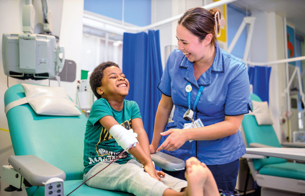 Nurse and patient smiling at the hospital, the patient is a little boy being treated with a bandage on his right arm.