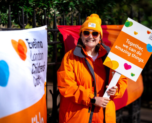 Woman smiling dressed in orange and wearing Evelina London Children