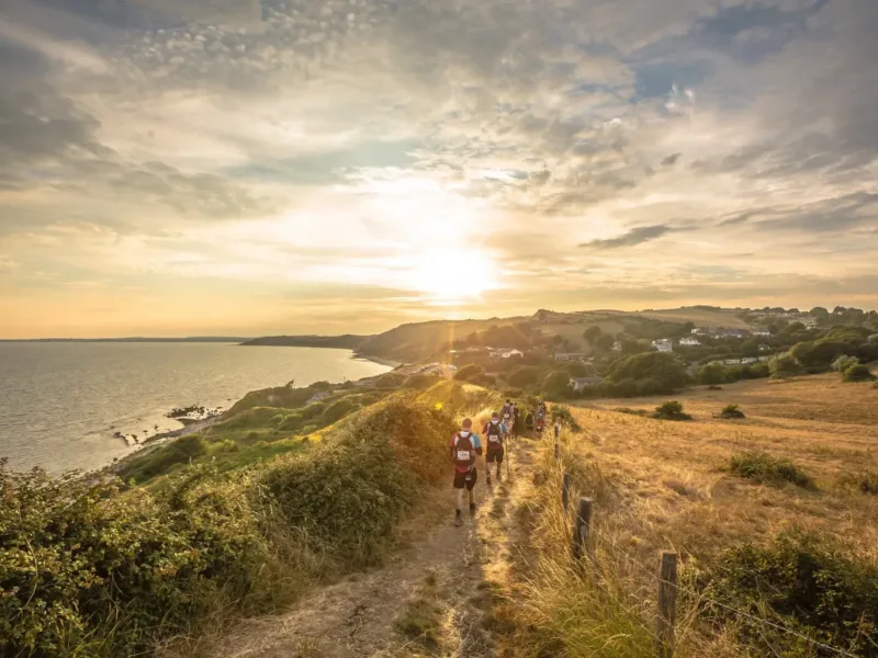 The Jurassic Coast landscape with people taking part in the ultra challenge hiking in the middle.
