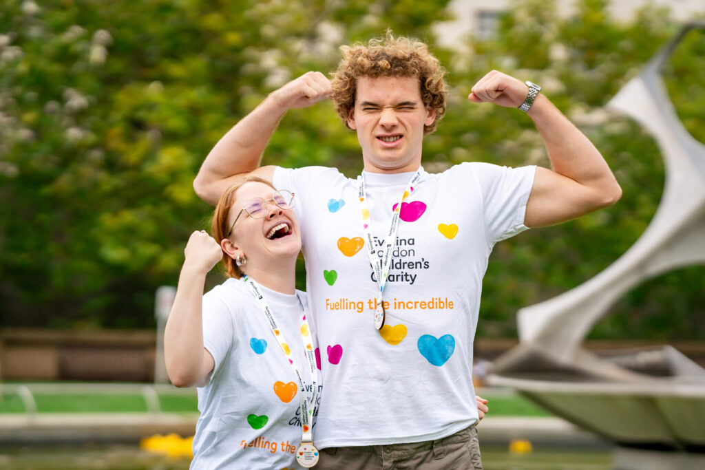 Two fundraisers flexing their arms wearing Evelina Children