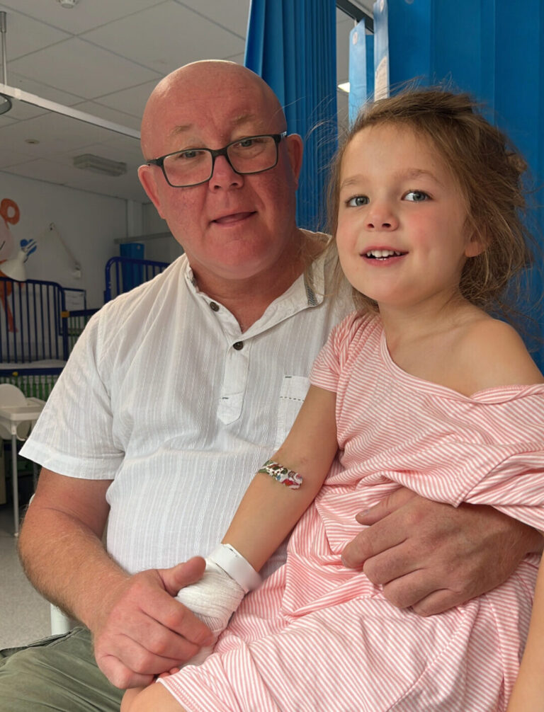 Grandad Paul with Indy on the right in a pink dress at Evelina London Hospital.