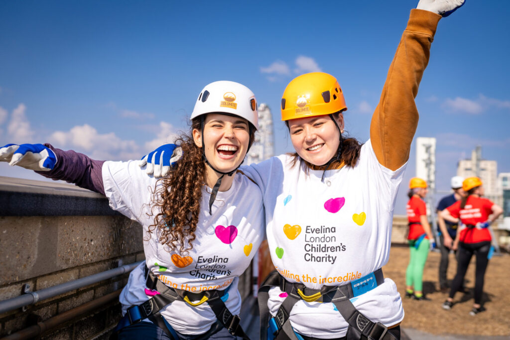 Two women appear to be cheering both wearing Evelina London Children