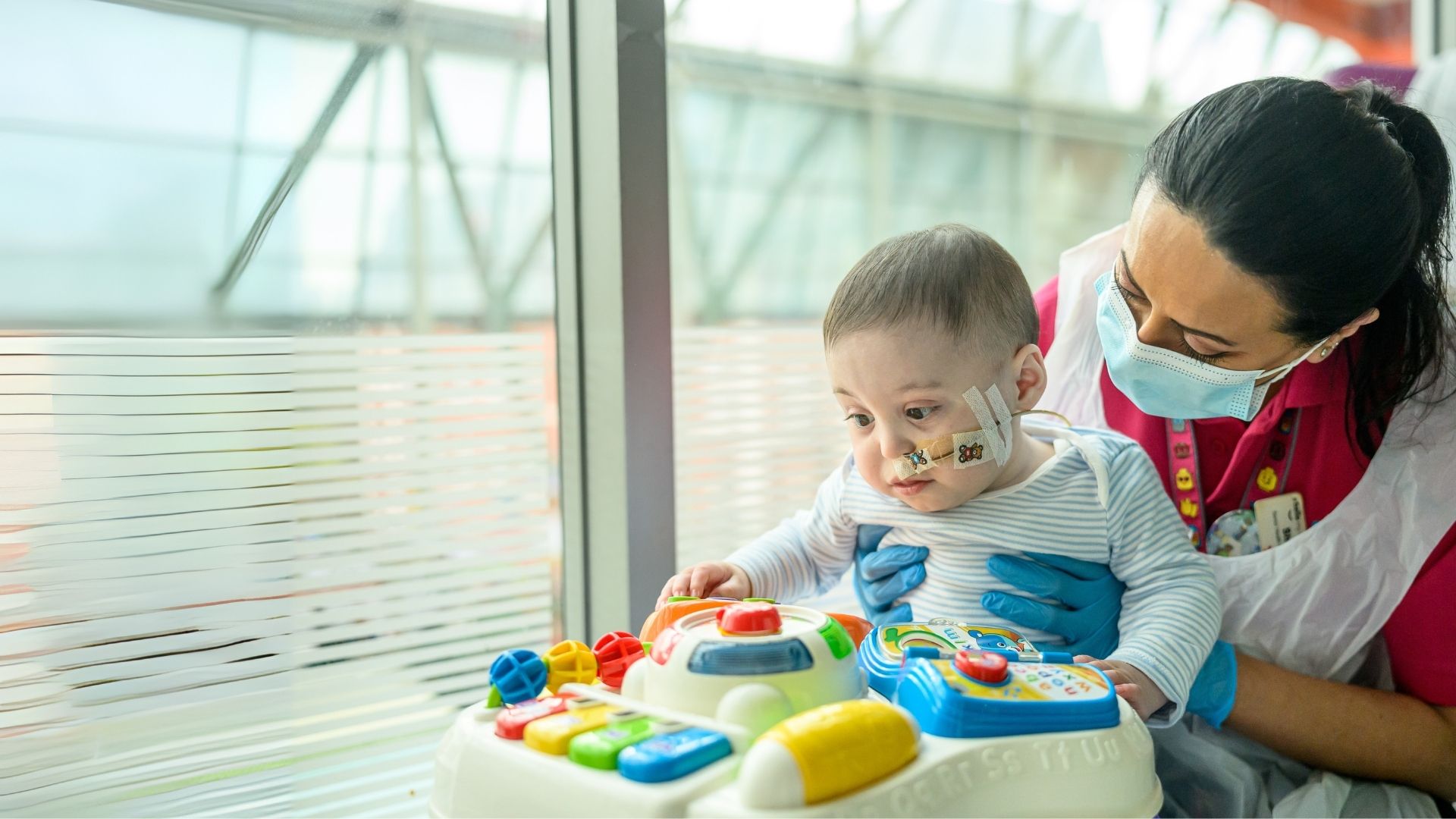 Baby Bertie at Evelina London playing with colourful toy with Play Specialist Shirin.