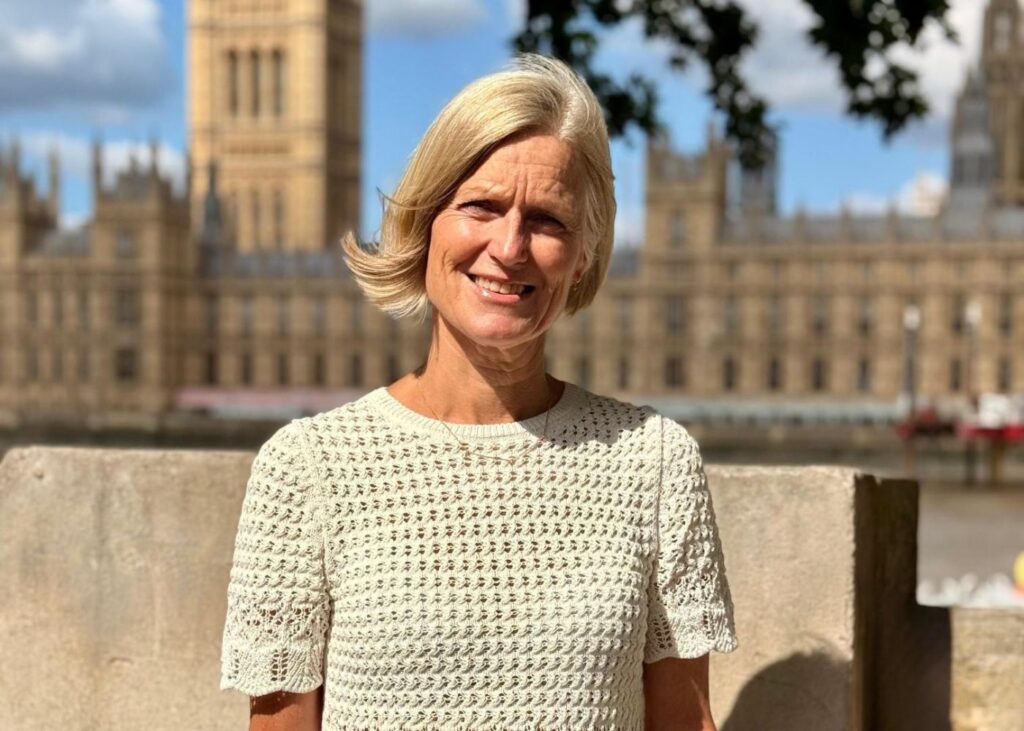 Tina in a cream crochet shore sleeve top in front of the Houses of Parliament.