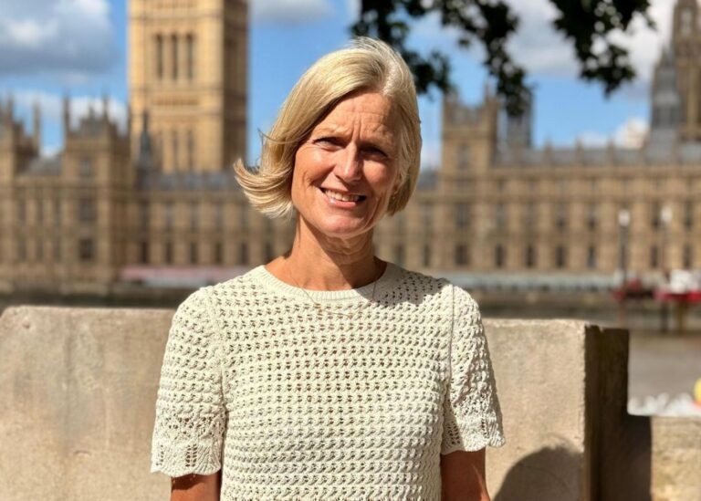 Tina in a cream crochet shore sleeve top in front of the Houses of Parliament.