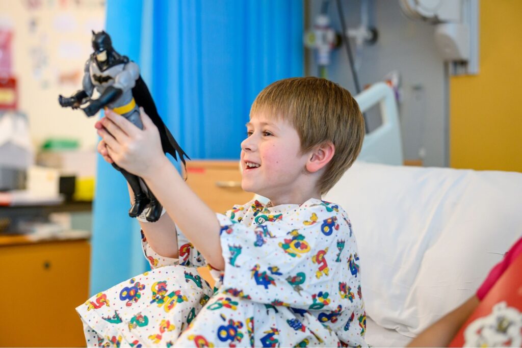 Nico playing with his batman toy in hospital bed at Evelina London Children