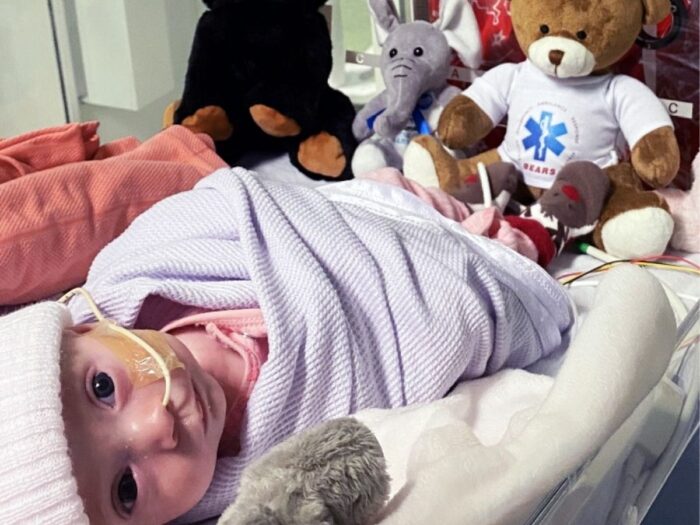 Baby Molly is in critical care unit cot, surrounded by plush toys.