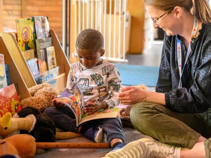 Child sat on the floor amongst lots of storybooks, he