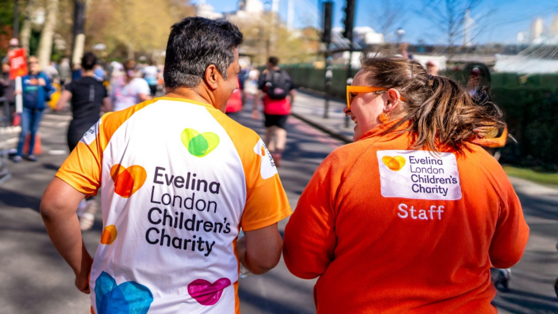 Evelina Children's Charity supporter running a marathon being cheered along by Evelina London Children's Charity in an orange fleece.
