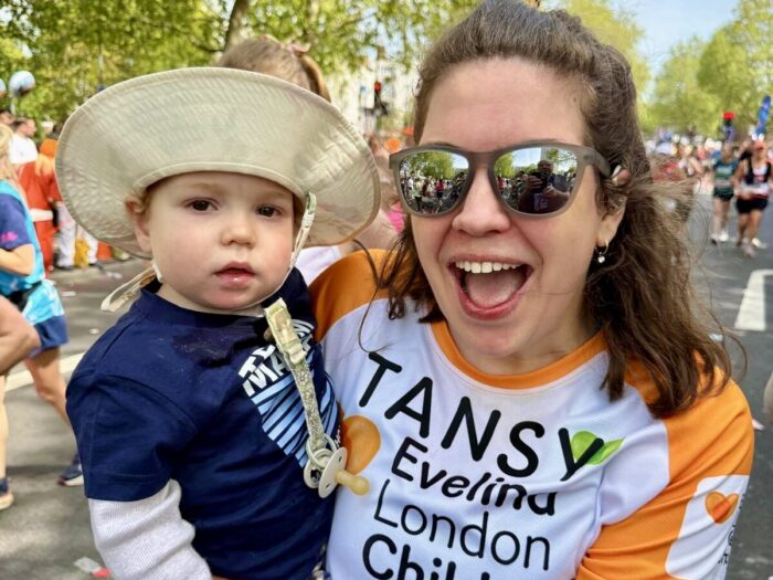 Tansy and Atlas at London Marathon event 2026. Tansy wearing sunglasses and appears to be smiling in an orange Evelina Children