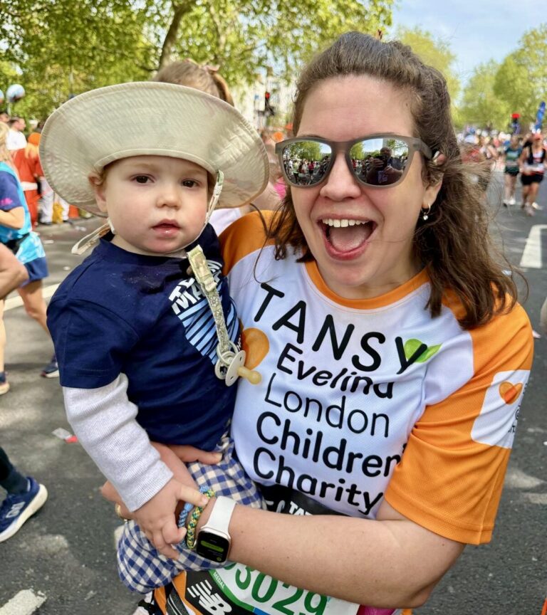 Tansy and Atlas at London Marathon event 2026. Tansy wearing sunglasses and appears to be smiling in an orange Evelina Children