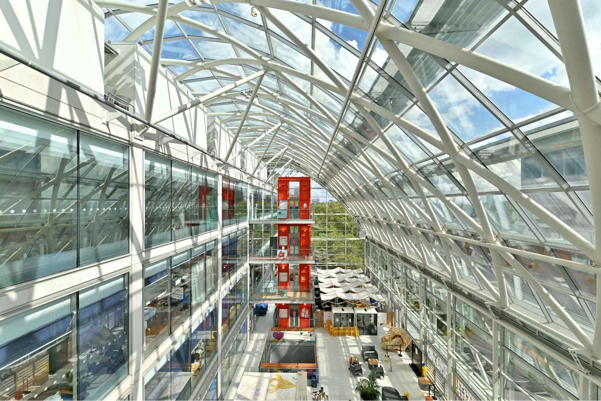 A view at the top of the Atrium of Evelina London Children's Hospital atrium, in the middle there is a red lift.