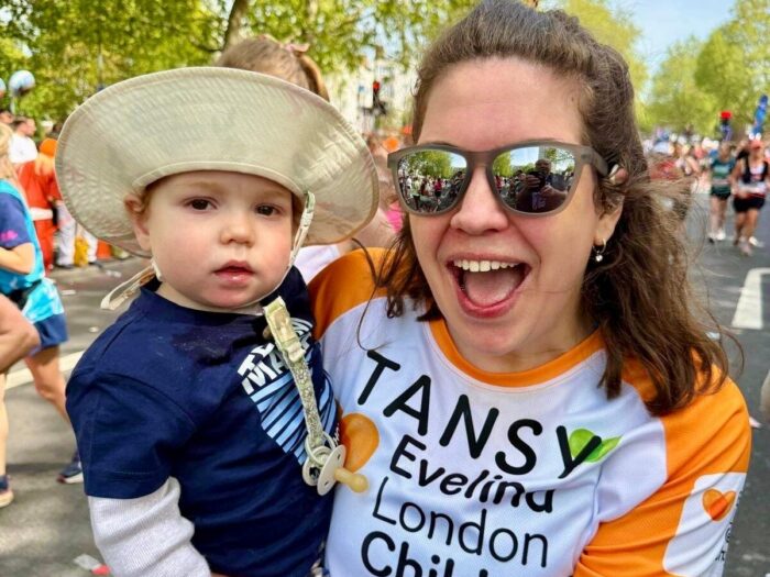 Tansy and Atlas at London Marathon event 2026. Tansy wearing sunglasses and appears to be smiling in an orange Evelina Children