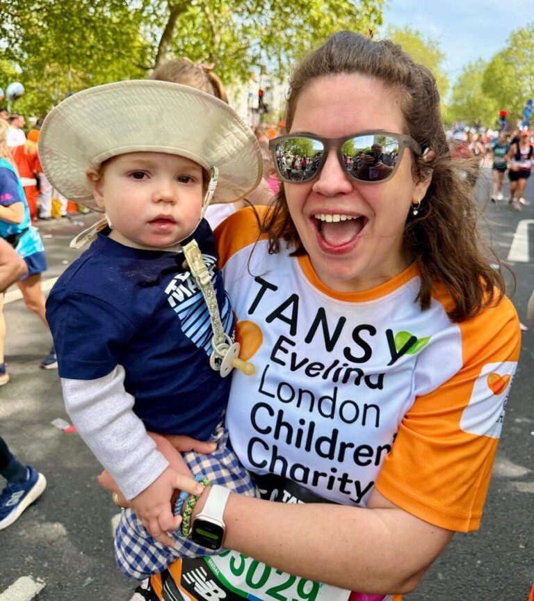 Tansy and Atlas at London Marathon event 2026. Tansy wearing sunglasses and appears to be smiling in an orange Evelina Children