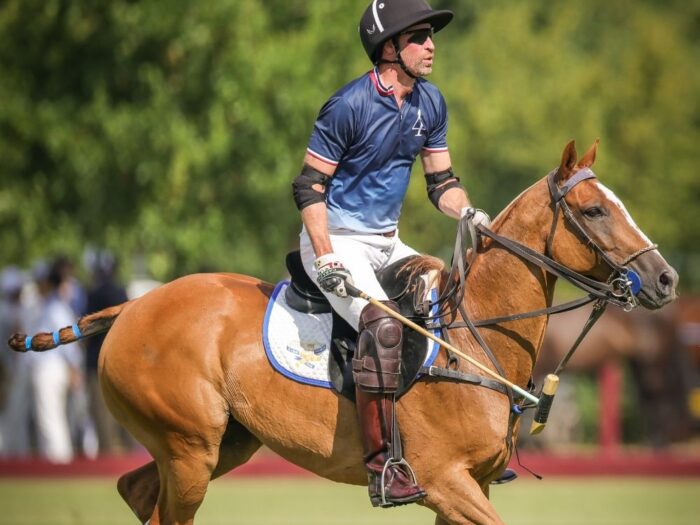 His Royal Highness The Prince of Wales competing at the polo fundraiser on a brown horse.